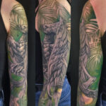 Tatouage - Phoenix en noir et gris et fond feuillages en couleurs sur l'épaule et bras